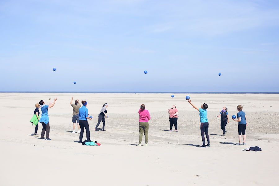 Eine Gruppe am Strand macht Bewegungsübungen mit Bällen Eine Gruppe am Strand macht Bewegungsübungen mit Bällen