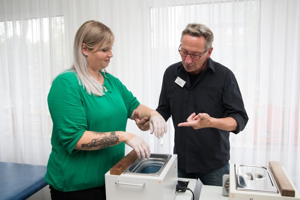 Eine Frau bei der Ergotherapie mit einem Wachsbad Eine Frau bei der Ergotherapie mit einem Wachsbad