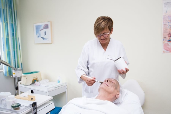 Frau verabreicht einem Mann eine Gesichtsmaske Frau verabreicht einem Mann eine Gesichtsmaske