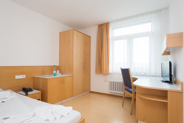 Zimmer mit Bett, Schrank, Schreibtisch und Fenster Zimmer mit Bett, Schrank, Schreibtisch und Fenster